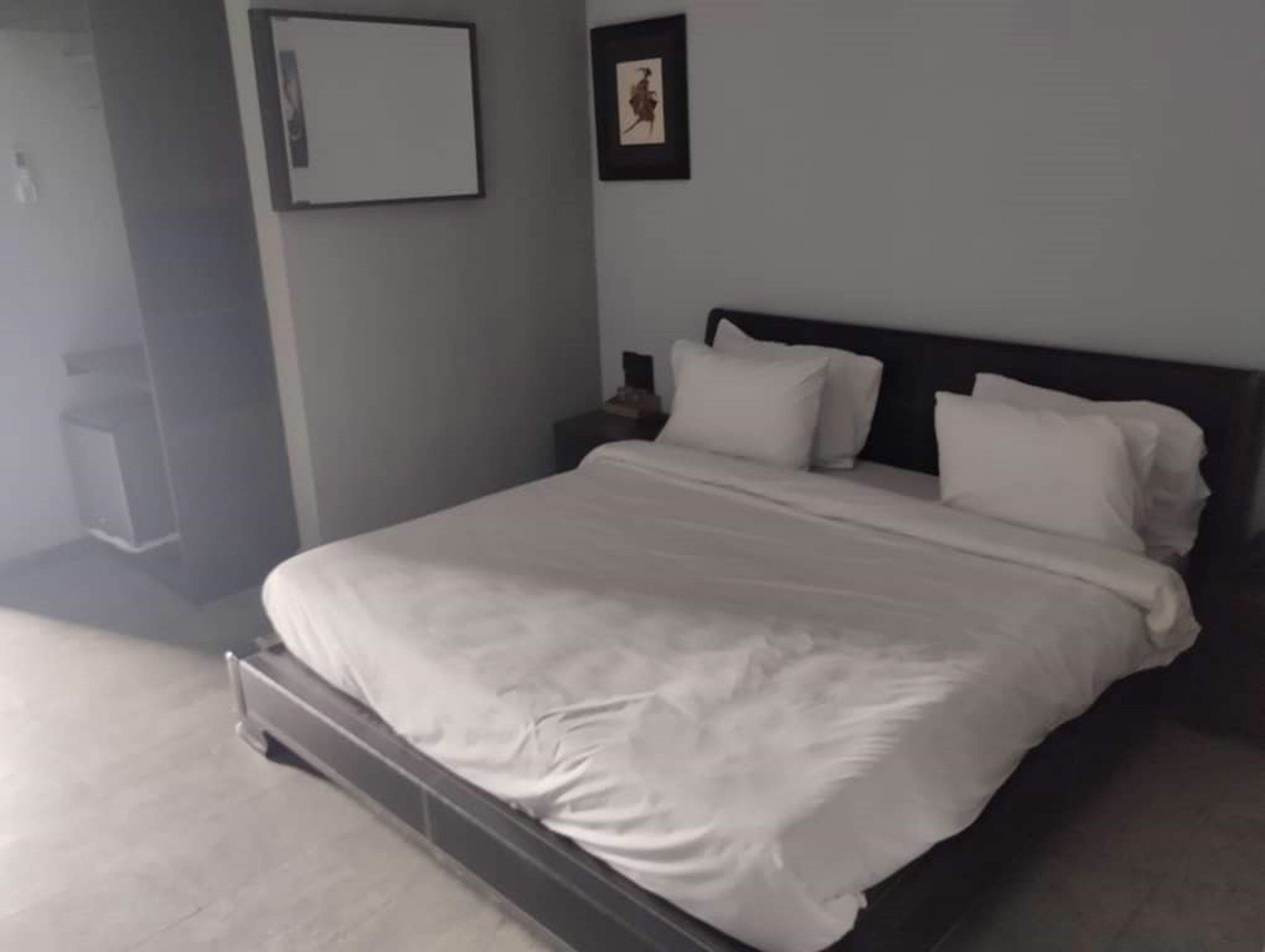 A neatly made bed with white linens in a hotel room.