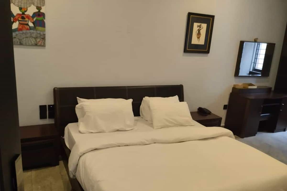 A hotel room with a bed, a nightstand, a dresser, a framed picture on the wall, and a television on the dresser.