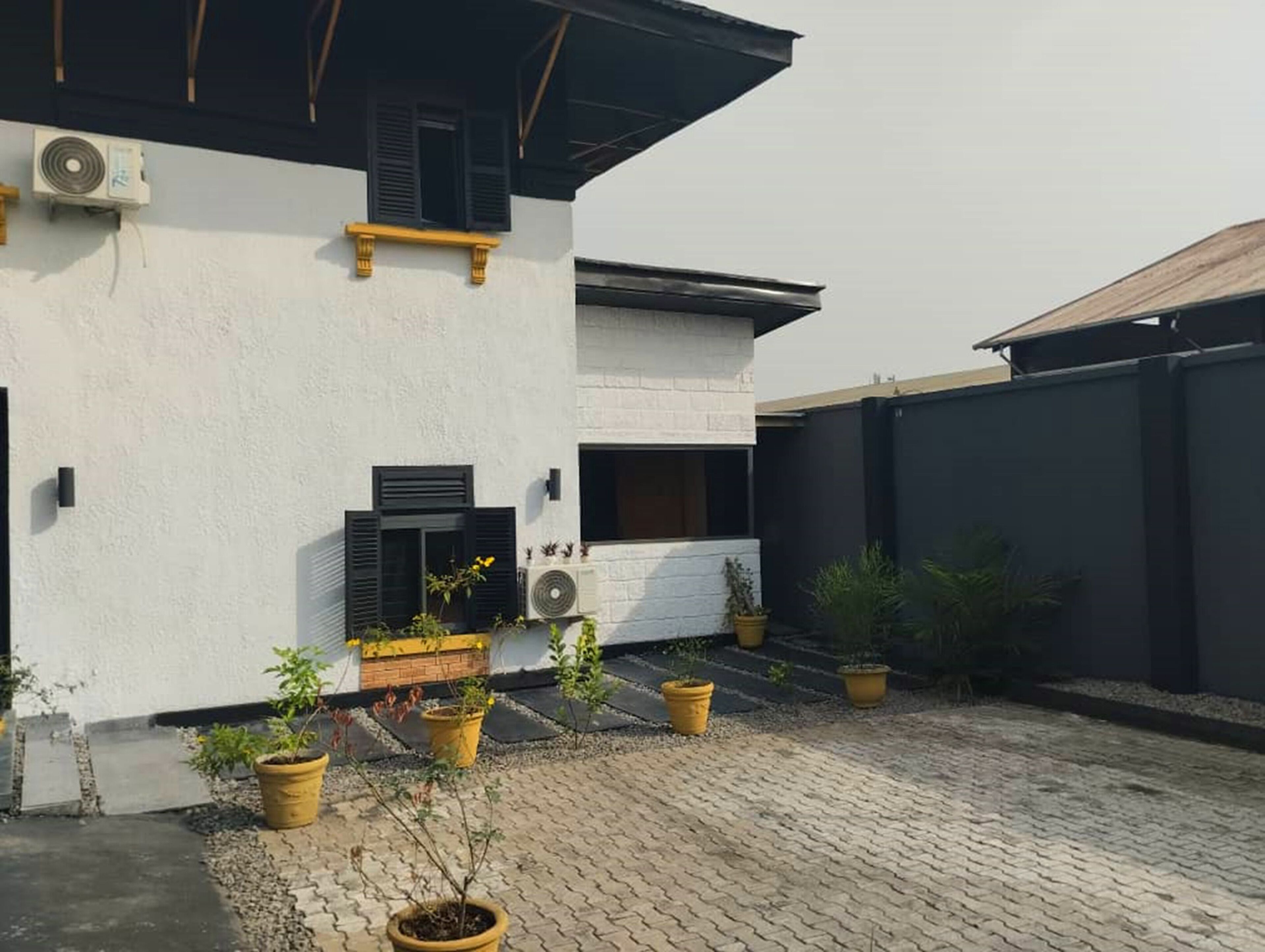A modern building with white walls, black shutters, and potted plants.