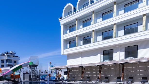 A hotel with a pool area, including a water slide and lounge chairs. - Belenli Resort Hotel  (Serik)