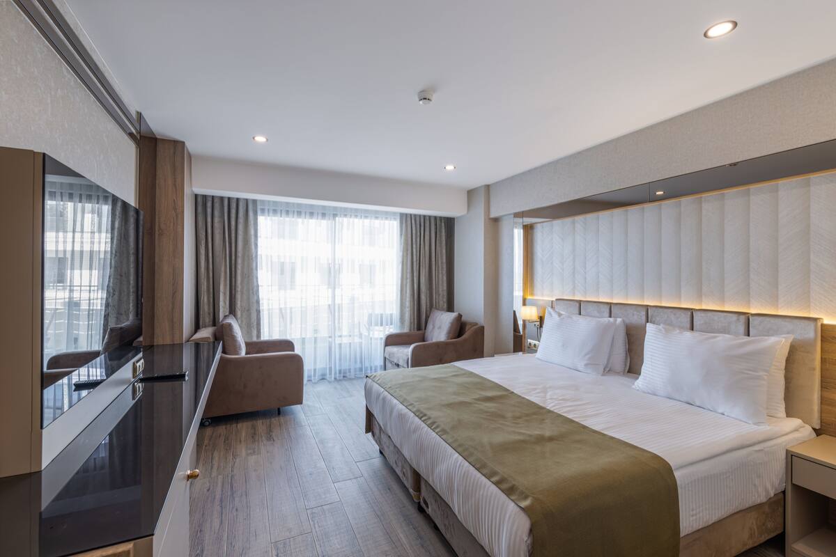 Una habitación de hotel moderna con una cama grande, un escritorio y una zona de estar.