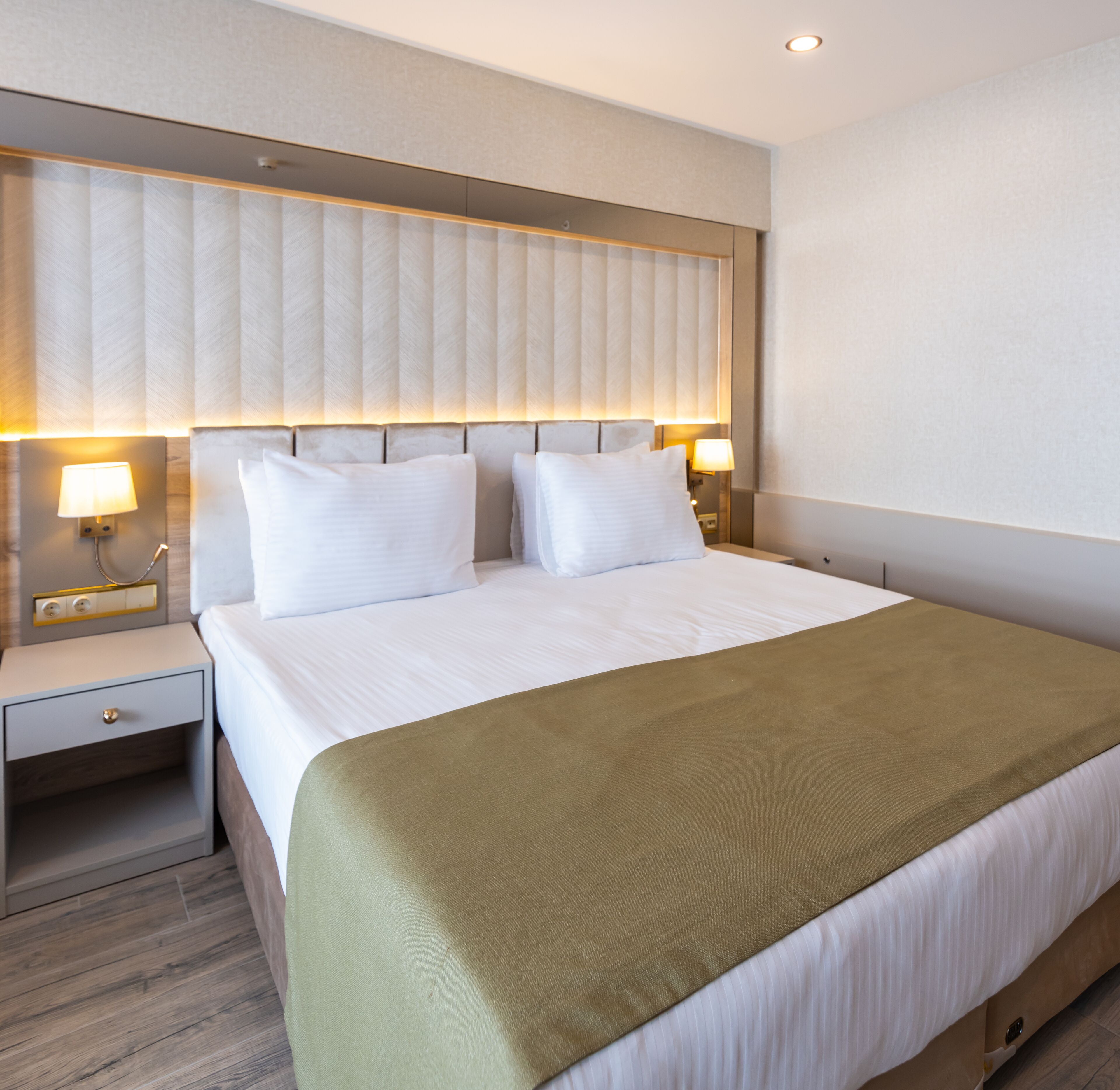 Een hotelkamer met een groot bed, twee nachtkastjes en een hoofdeinde met verticale lijnen.