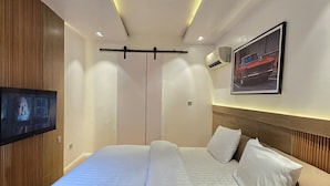 Une chambre d’hôtel moderne avec un grand lit, un téléviseur à écran plat fixé au mur et un tableau représentant une voiture.