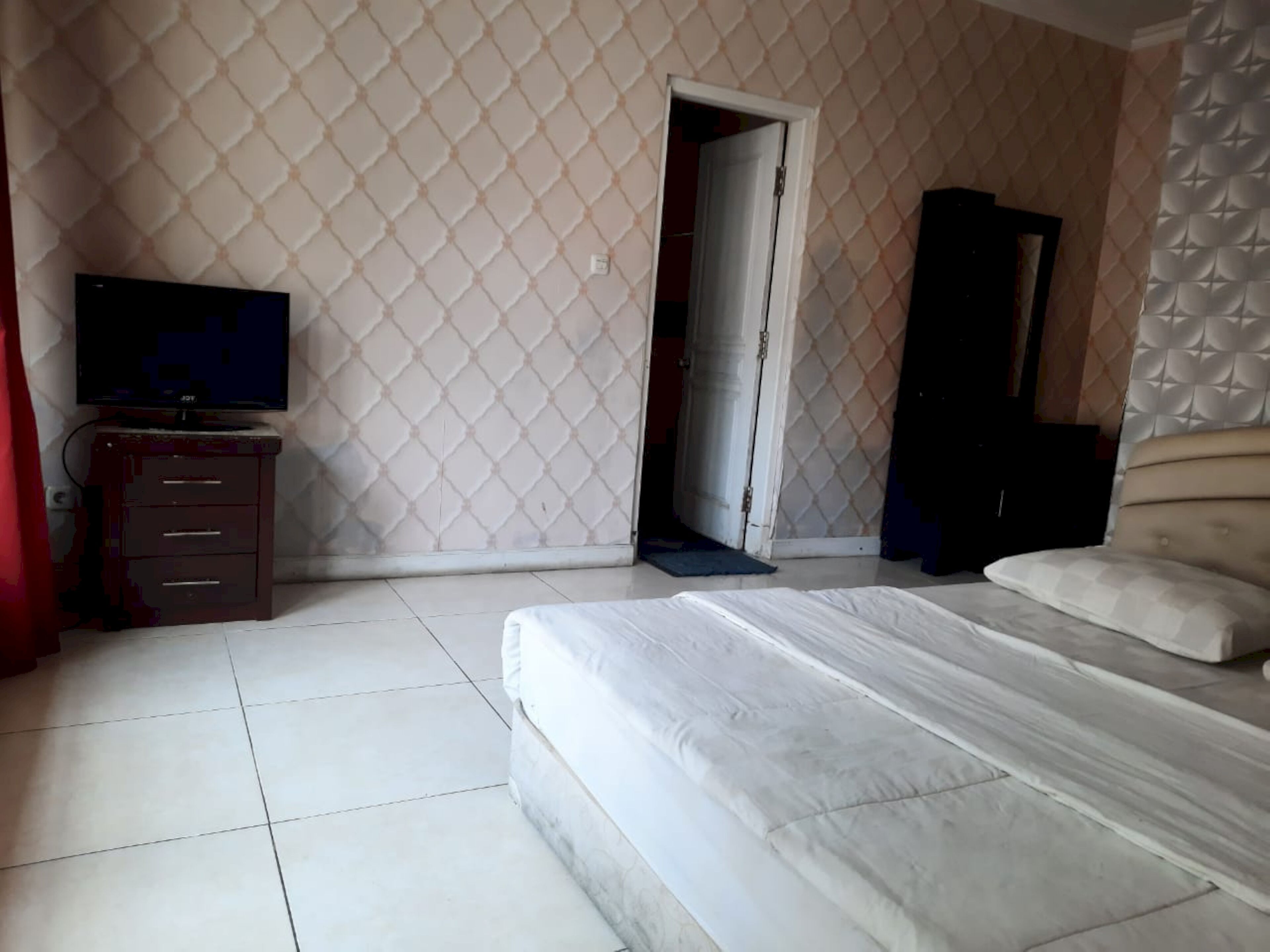 A bedroom with a bed, a television on a dresser, and a wardrobe.
