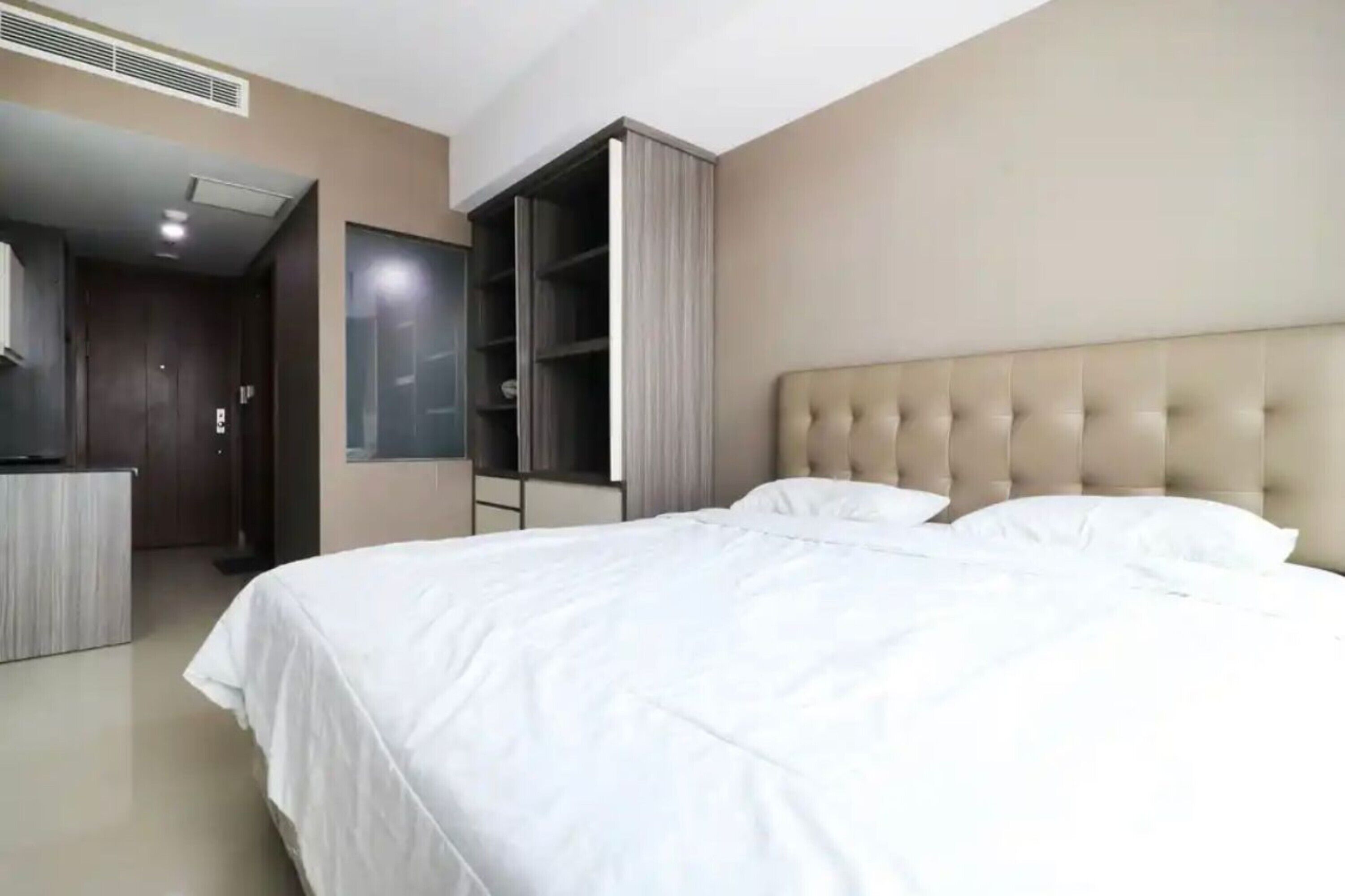 A hotel room with a large bed, a wardrobe, and a mirror.