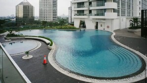 A modern building with a large, curved swimming pool surrounded by a deck. - Collection O 93707 Rooms By U (Berastagi)