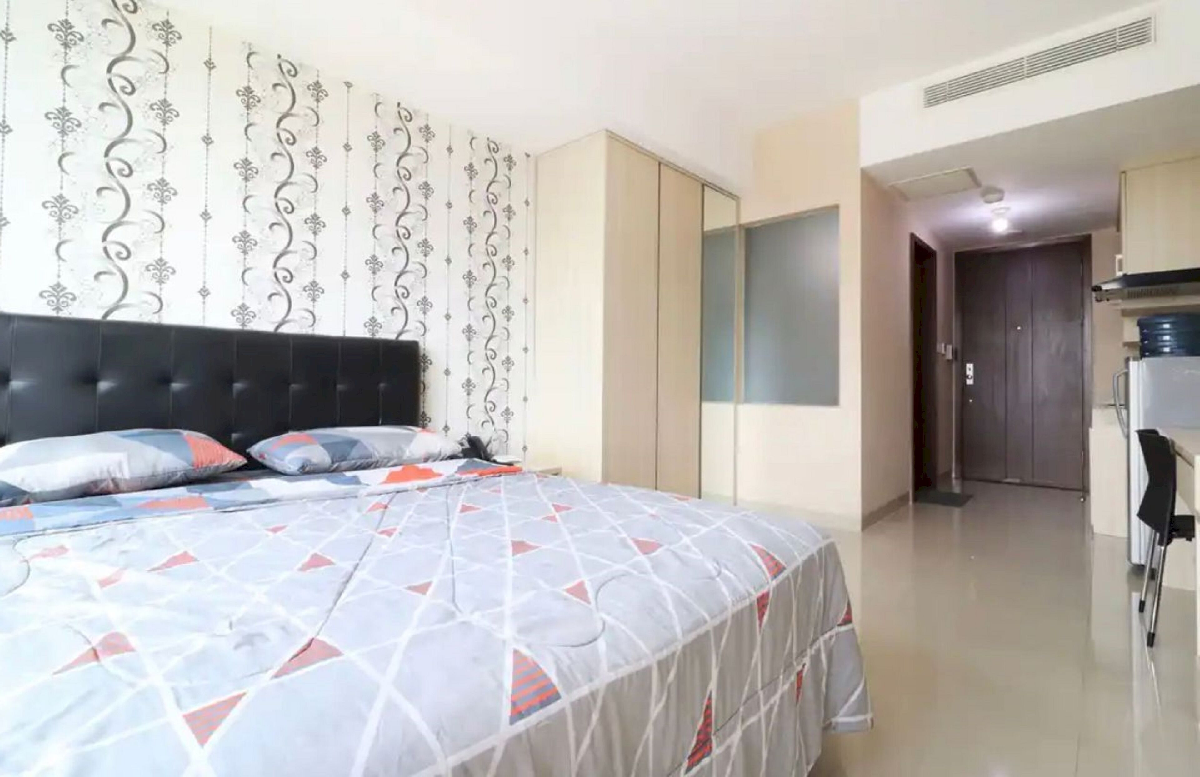 Un dormitorio con cama, armario y espejo.