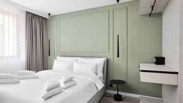 Una habitación de hotel moderna con una cama grande, una mesita de noche, una pequeña mesa redonda y un estante empotrado.