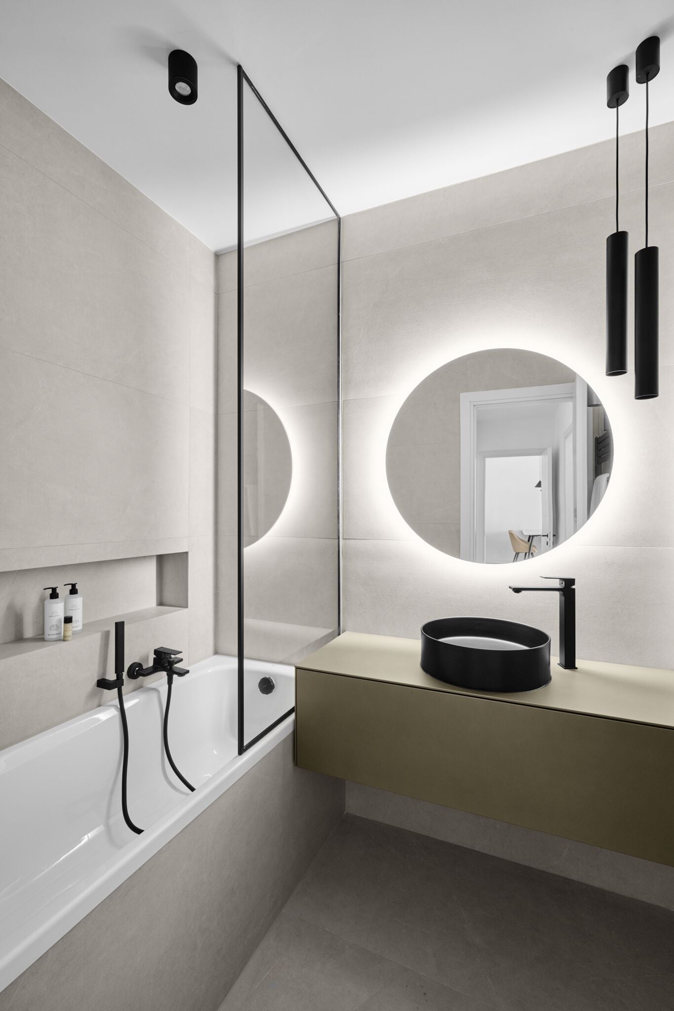 A modern bathroom with a round mirror, a bathtub, and a sink.