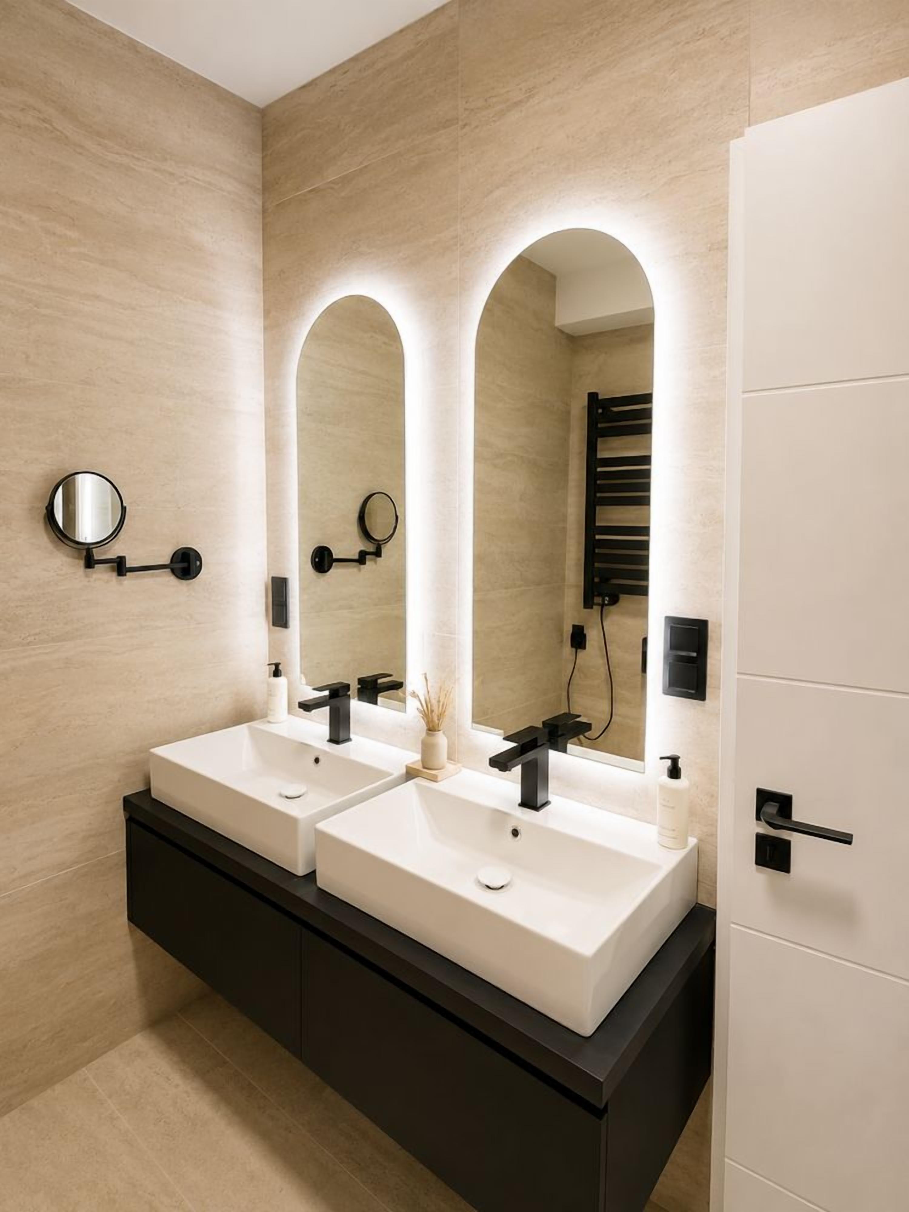 A modern bathroom with two sinks, a large mirror, and a towel rack.