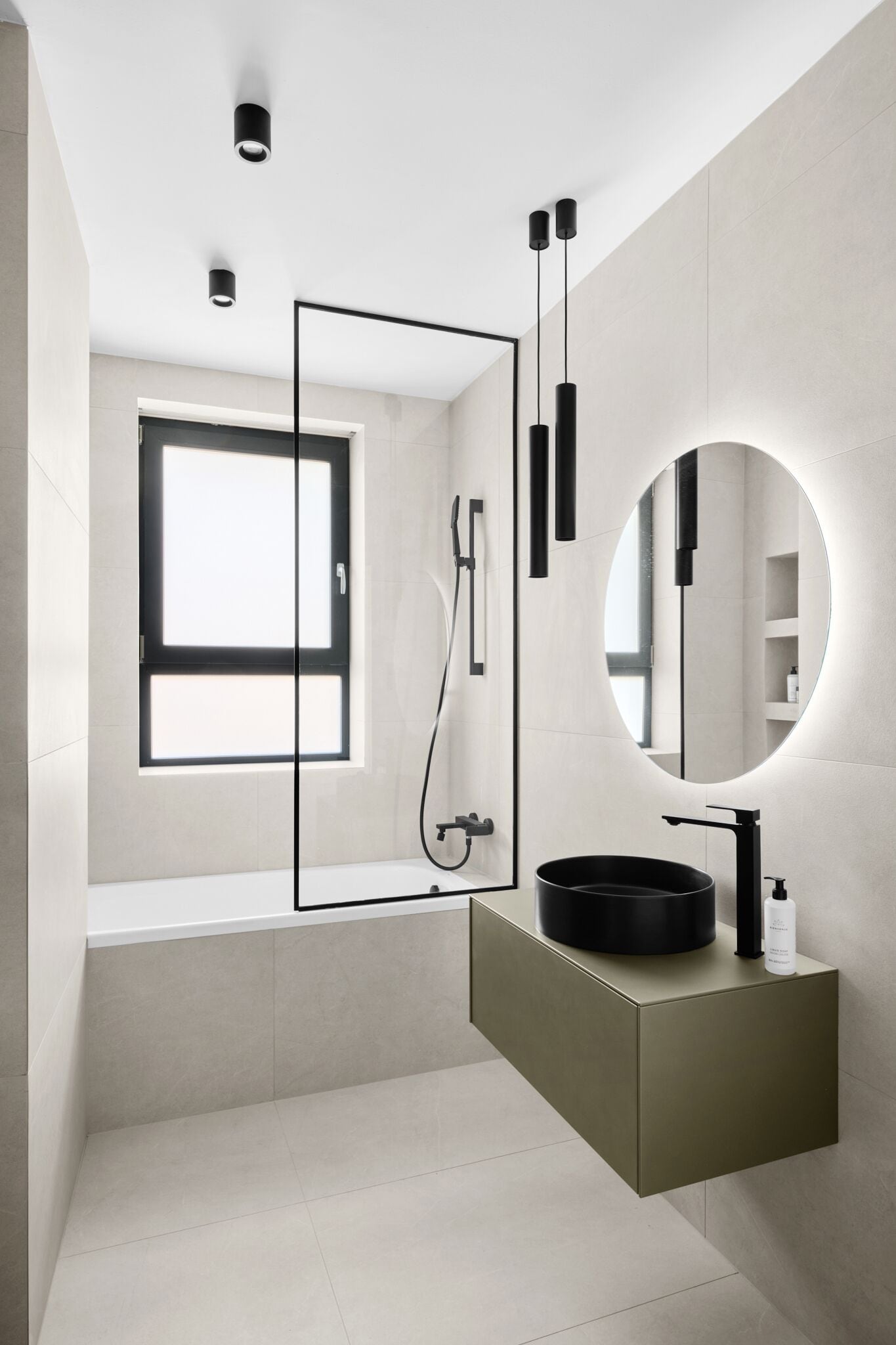 A modern bathroom with a rectangular mirror, a round mirror, a bathtub, and a toilet.