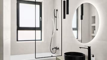 A modern bathroom with a rectangular mirror, a round mirror, a bathtub, and a toilet.