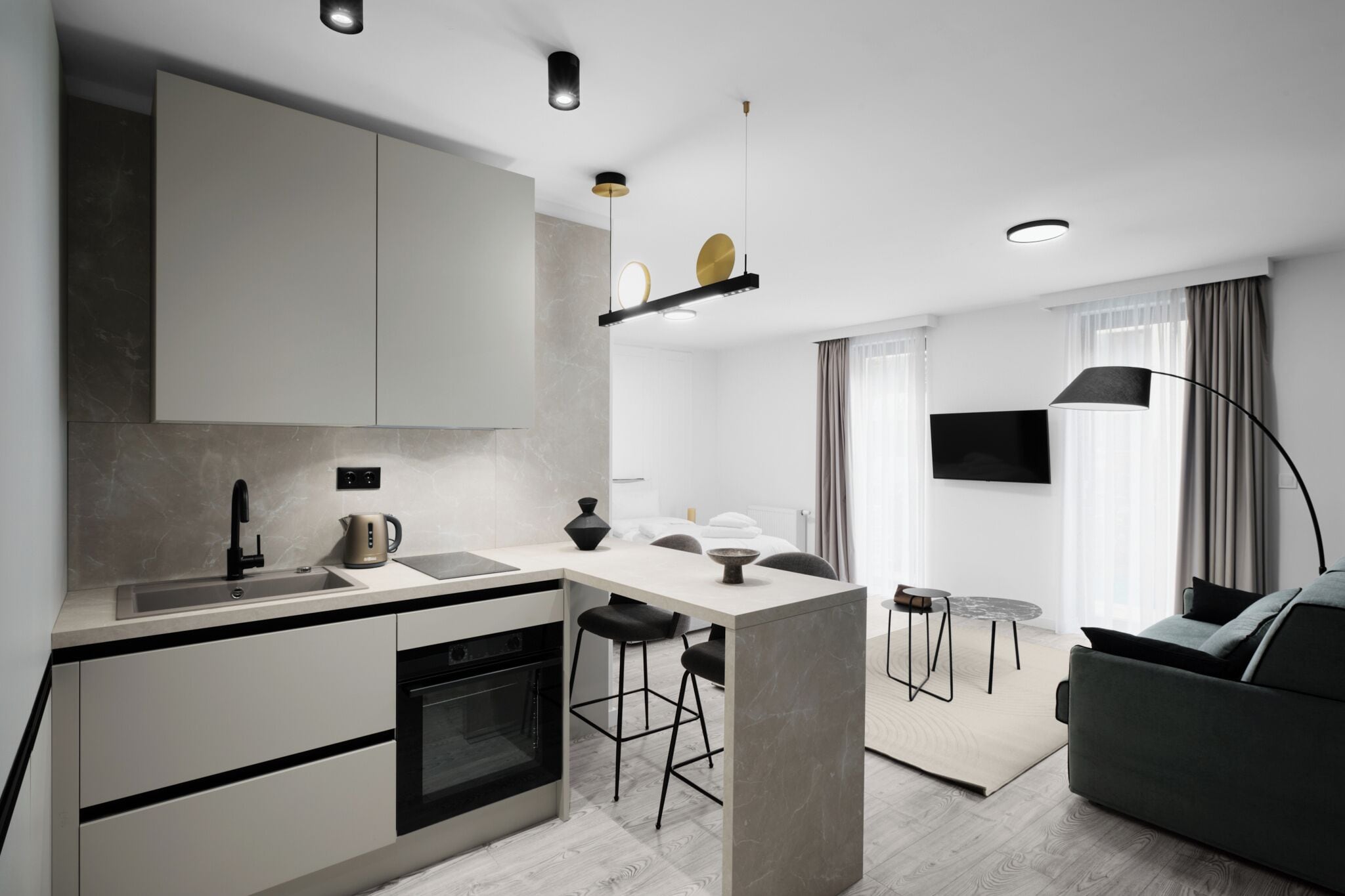 A modern kitchen with a central island, built-in appliances, and a dining area with a sofa and a lamp.