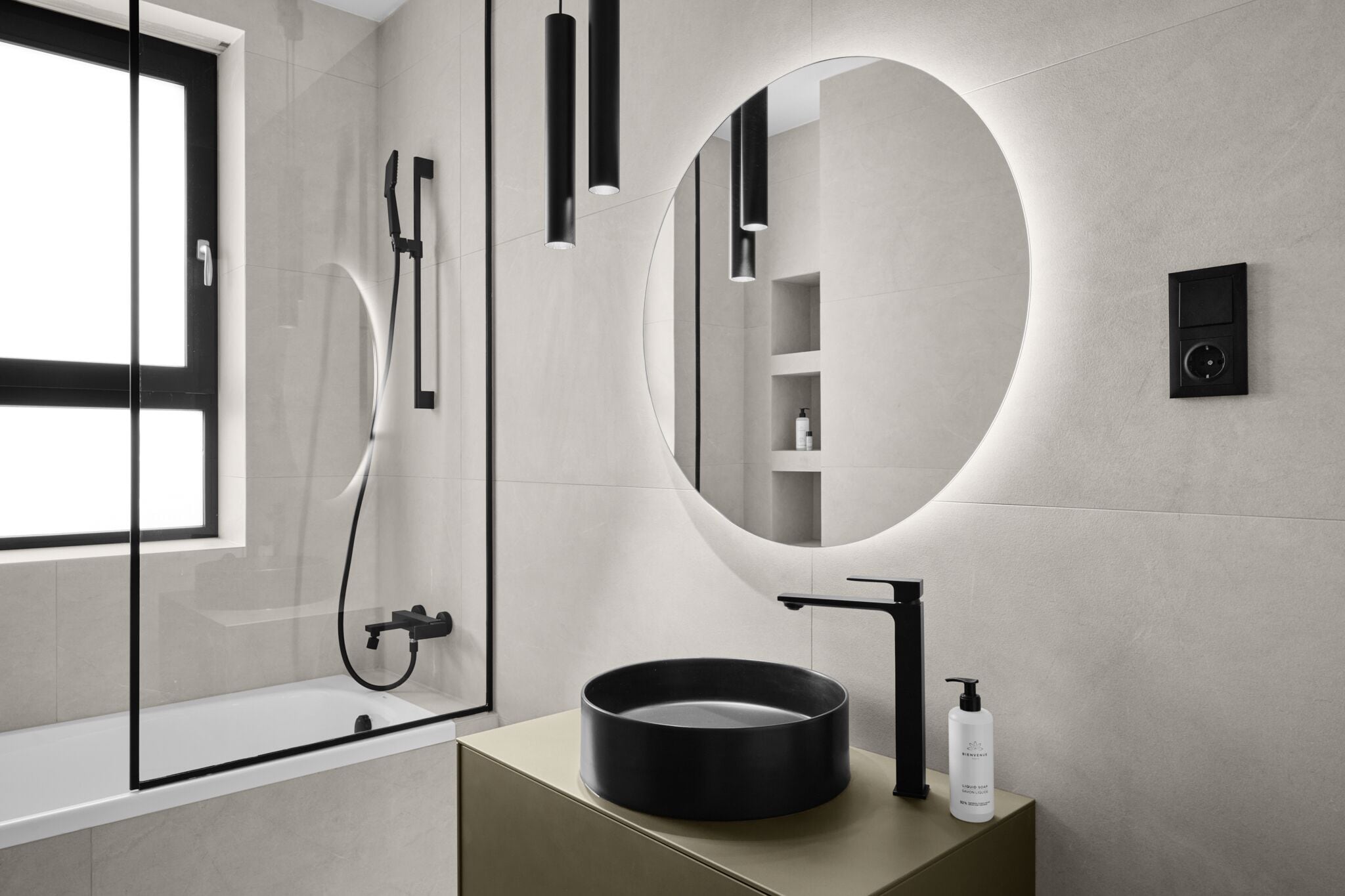 A modern bathroom with a round mirror, a bathtub, and a sink.