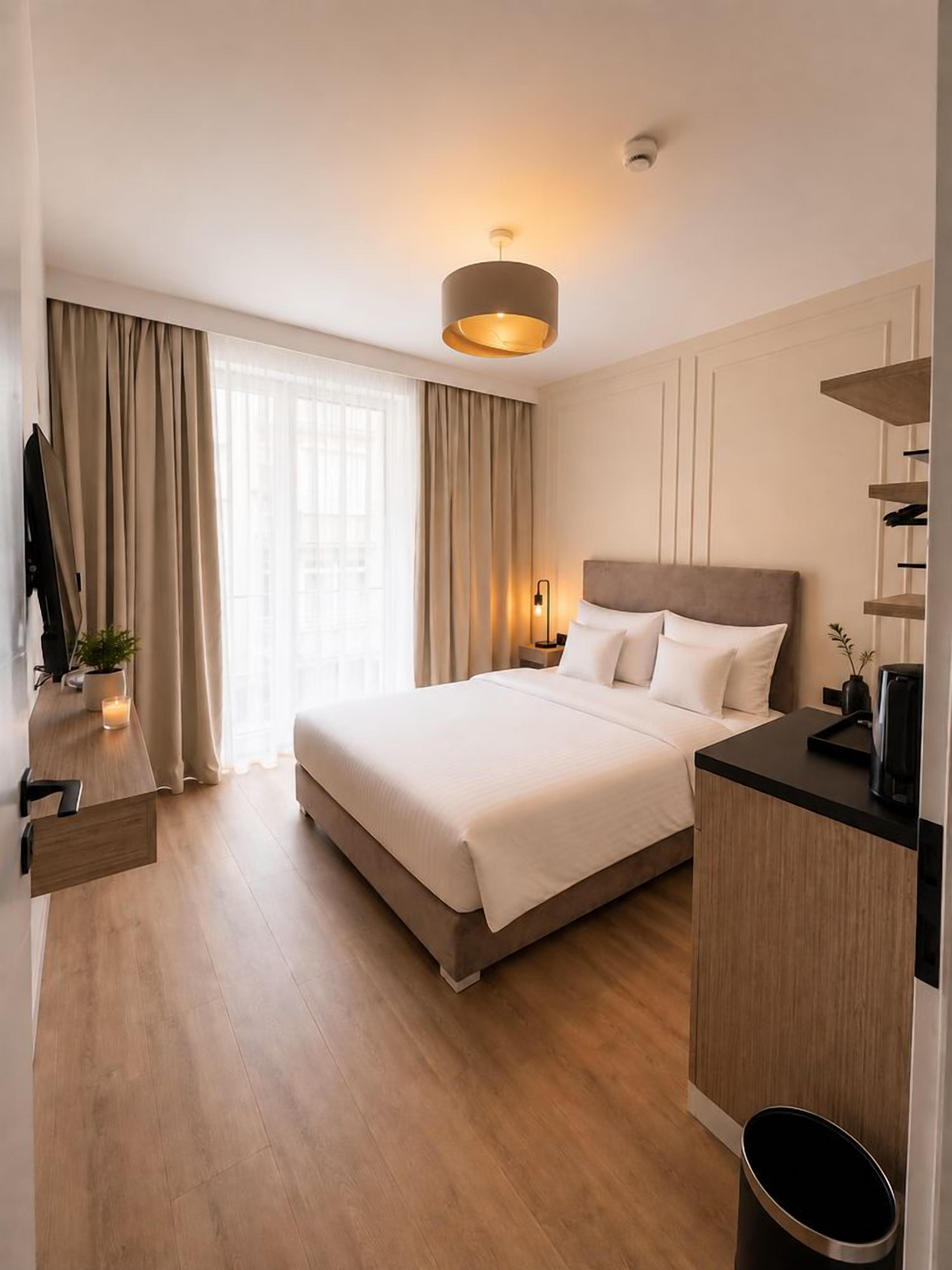 Ein modernes Hotelzimmer mit einem großen Bett, einem Nachttisch und einem Schreibtisch.