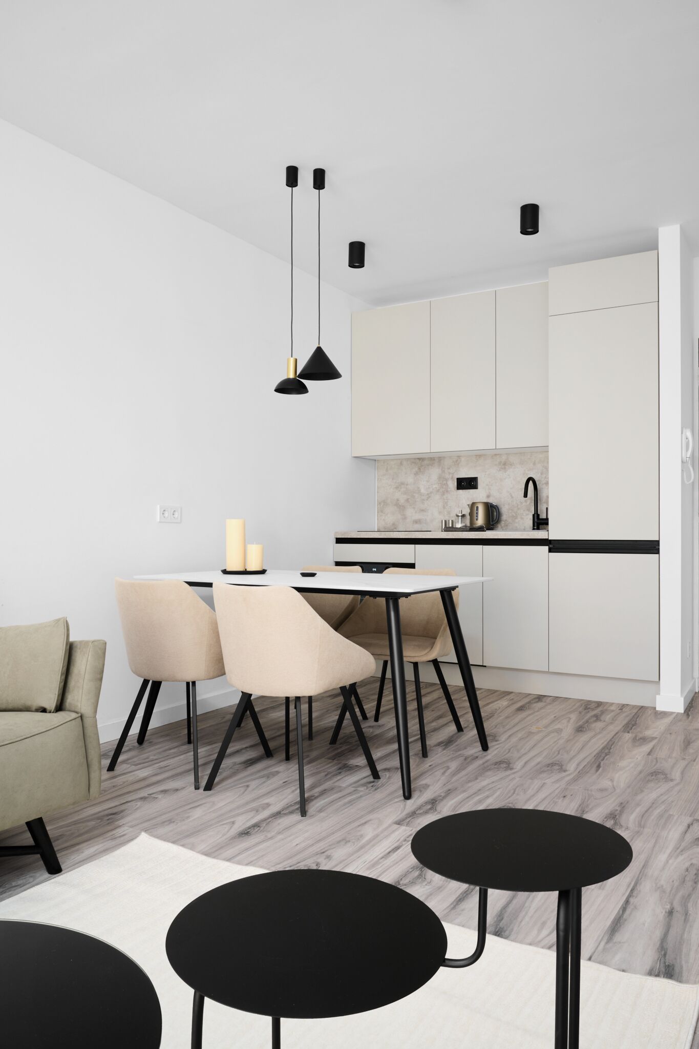 A modern kitchen with white cabinets, a black countertop, and a dining area with a round table and chairs.