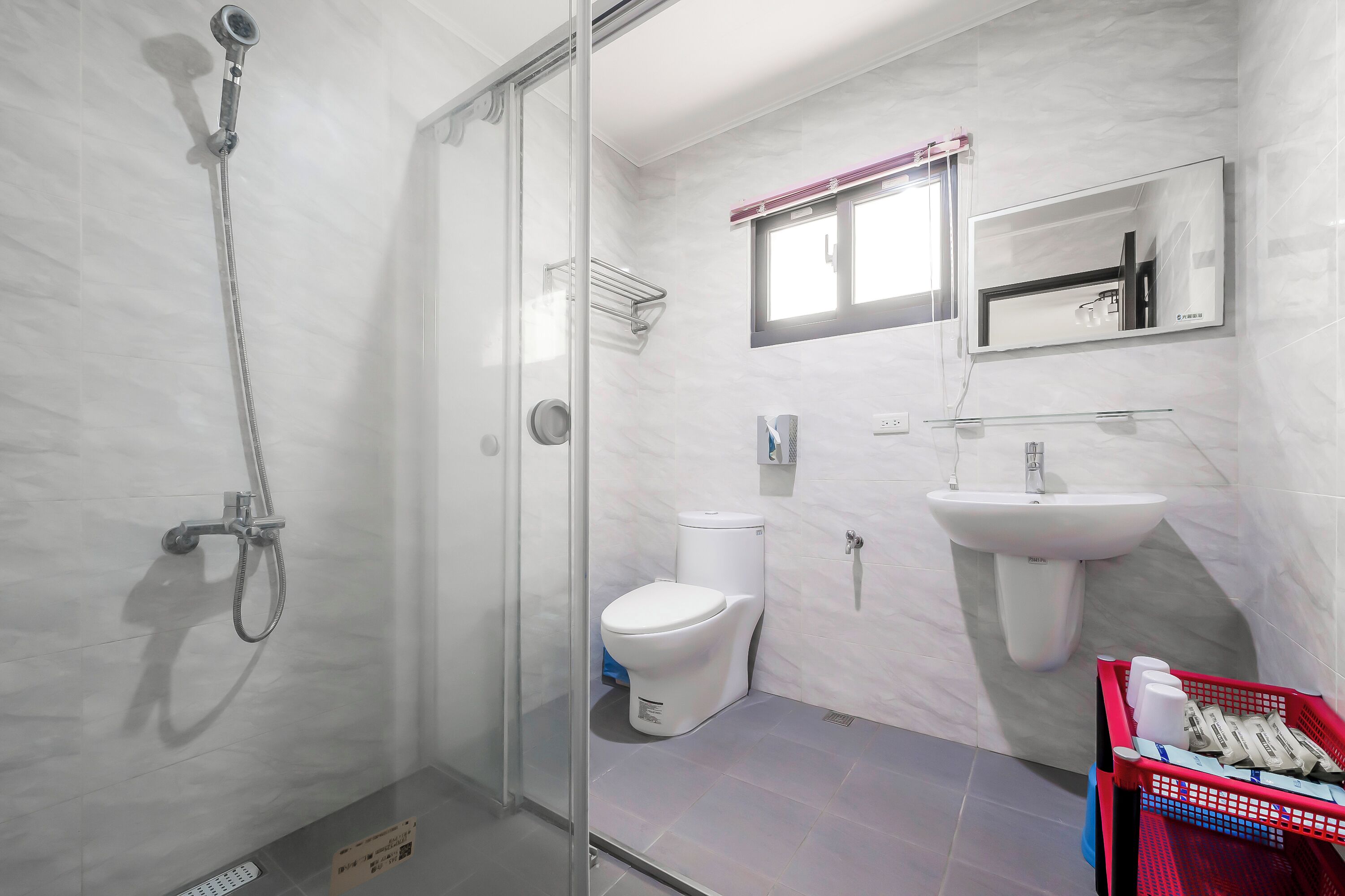 A modern bathroom with a glass-enclosed shower, a white toilet, a sink, and a mirror.