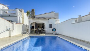 Una piscina con un edificio blanco al fondo.