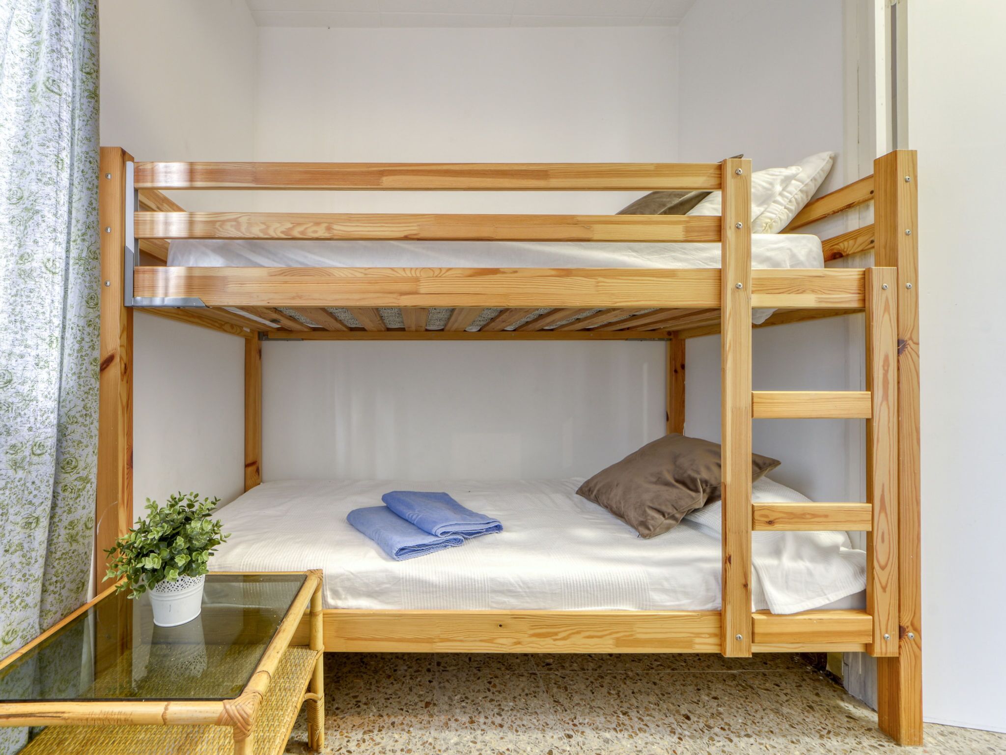 A bunk bed with a small table and a potted plant beside it.