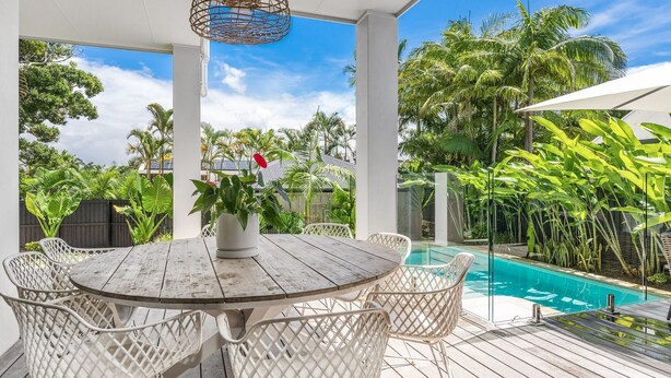 A covered outdoor area with a pool, surrounded by lush greenery and white wicker furniture. - Byron Bay Accom - Sunset on Massinger - 60 Massinger Street - Pets on Request (Byron Bay)