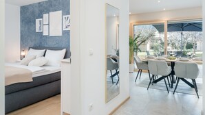 Quarto moderno com cama, mesa de cabeceira e parede decorada com obras emolduradas.