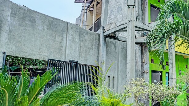 Un edificio de hormigón con una verja metálica, rodeado de abundante vegetación.