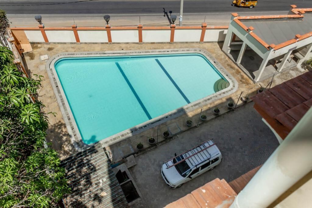 Una piscina rectangular con borde de azulejos, rodeada por un muro bajo y una barandilla.