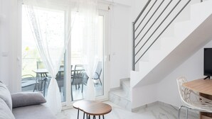 Una sala moderna con sofá, una mesa de madera y una escalera que sube a un nivel superior.