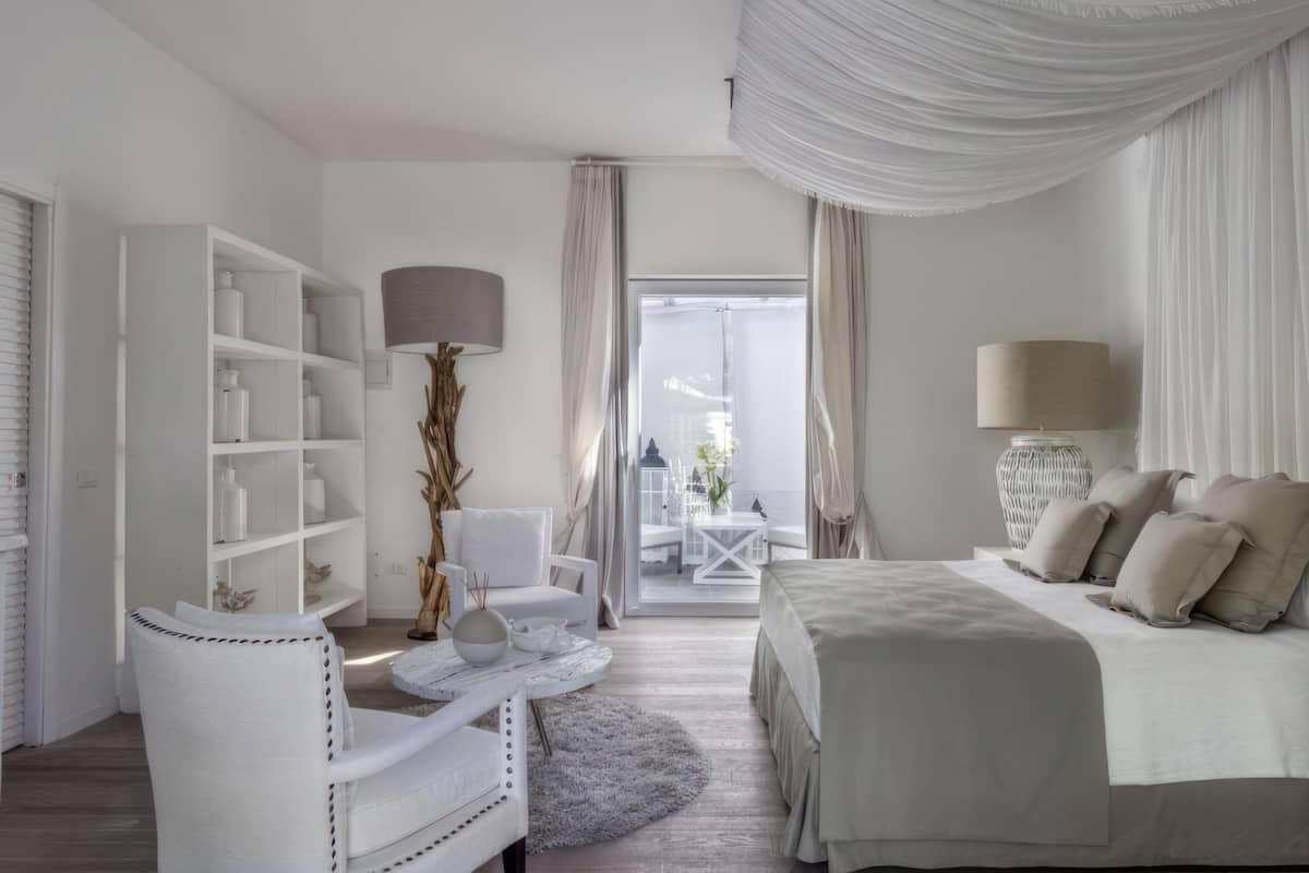 Ein modernes Schlafzimmer mit einem Bett, einem weißen Stuhl, einem kleinen Tisch und einem Bücherregal.