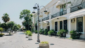 A street with a boutique hotel, outdoor seating, and palm trees. - Relais Corte degli Aragonesi (Ischia)