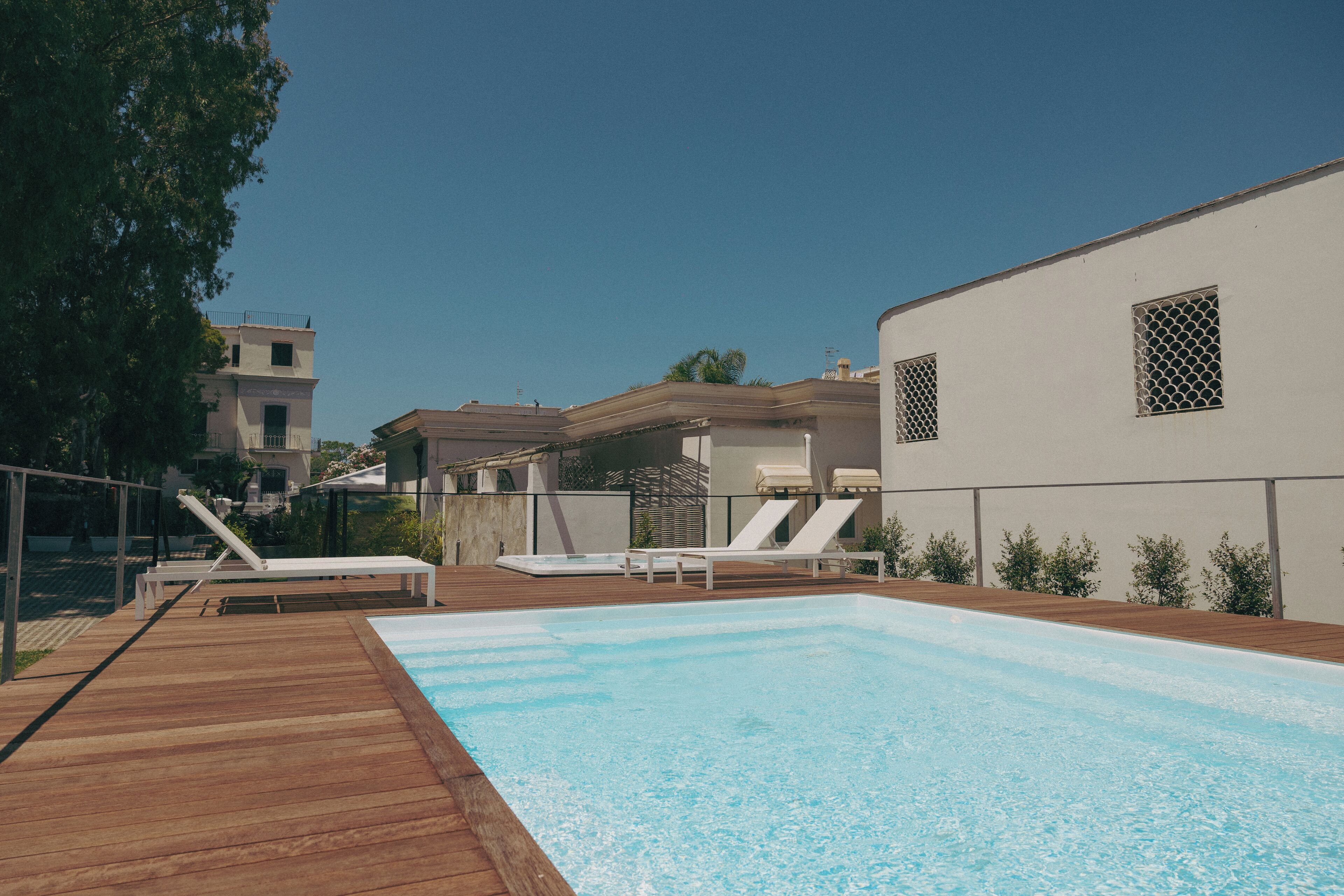 Una piscina al aire libre, sombrillas, sillones reclinables de piscina