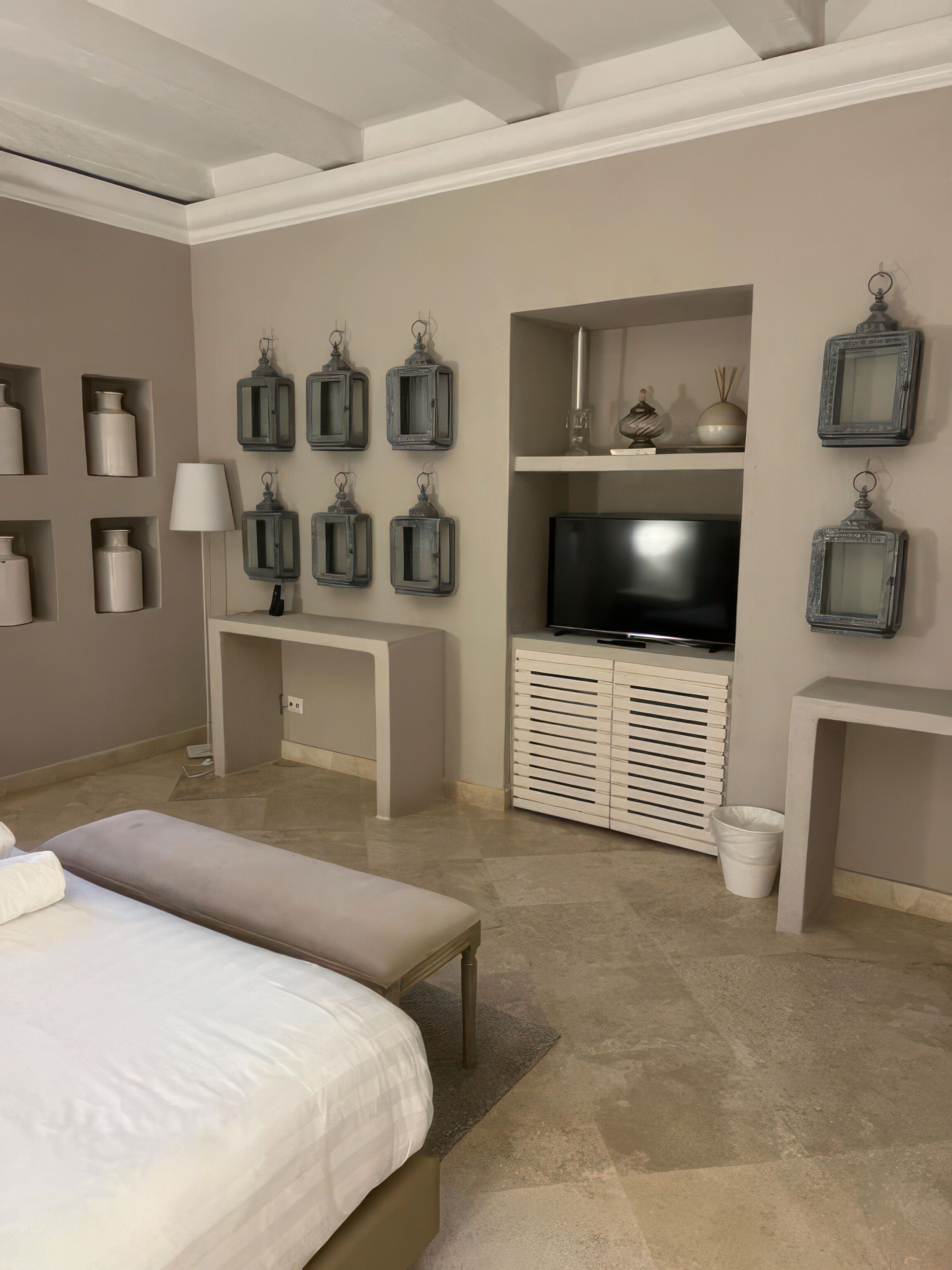 A modern bedroom with a large bed, a TV, and built-in storage units.
