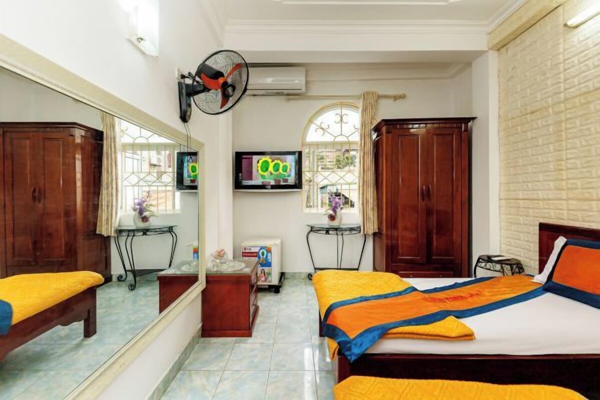 Une chambre d’hôtel avec un lit, un bureau, une chaise, un miroir, une télévision et une fenêtre.