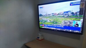Ein an der Wand befestigter Fernseher, der einen Nachrichtensender zeigt.