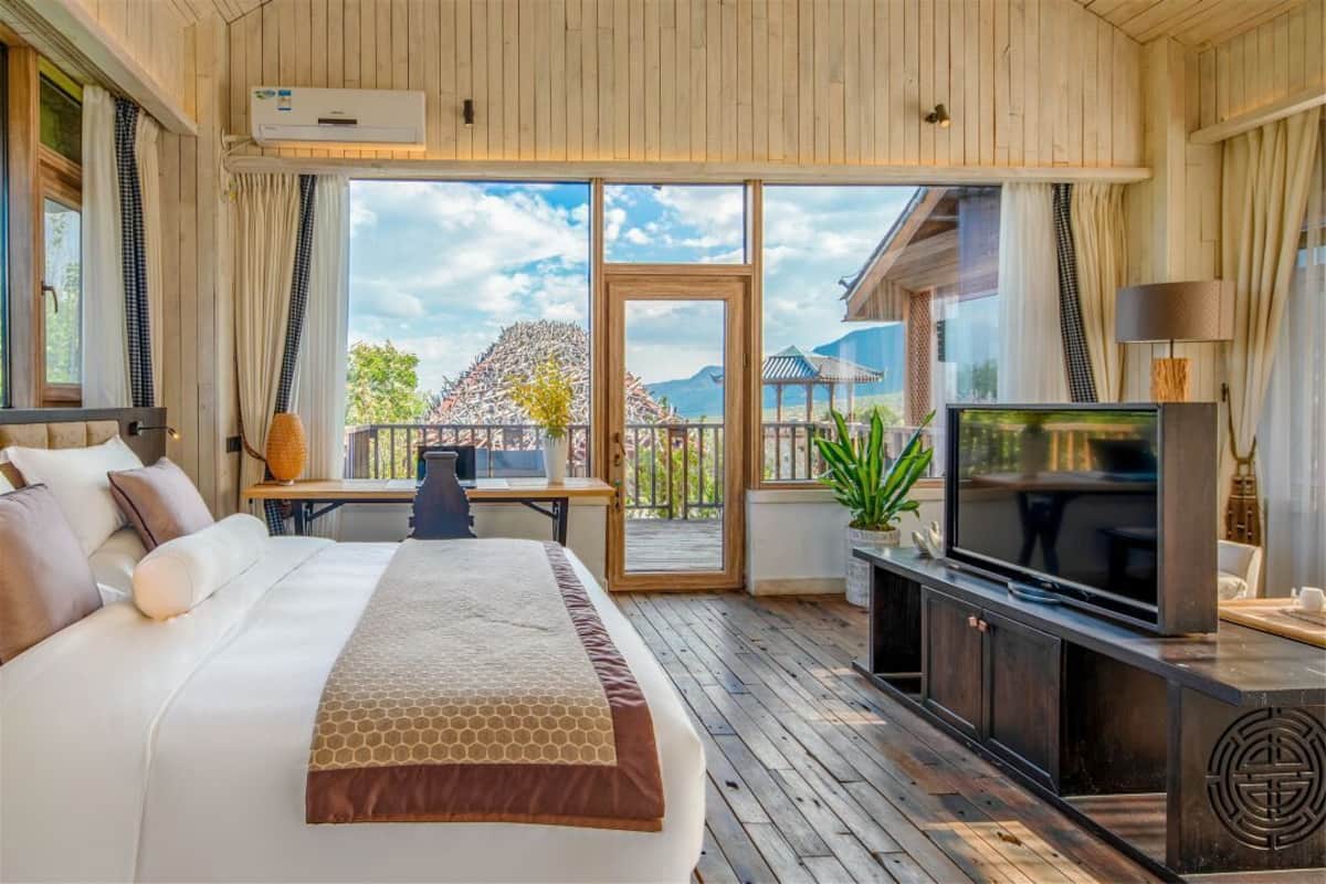 Une chambre dotée d’un grand lit, d’une télévision et d’un balcon offrant une vue sur les montagnes.