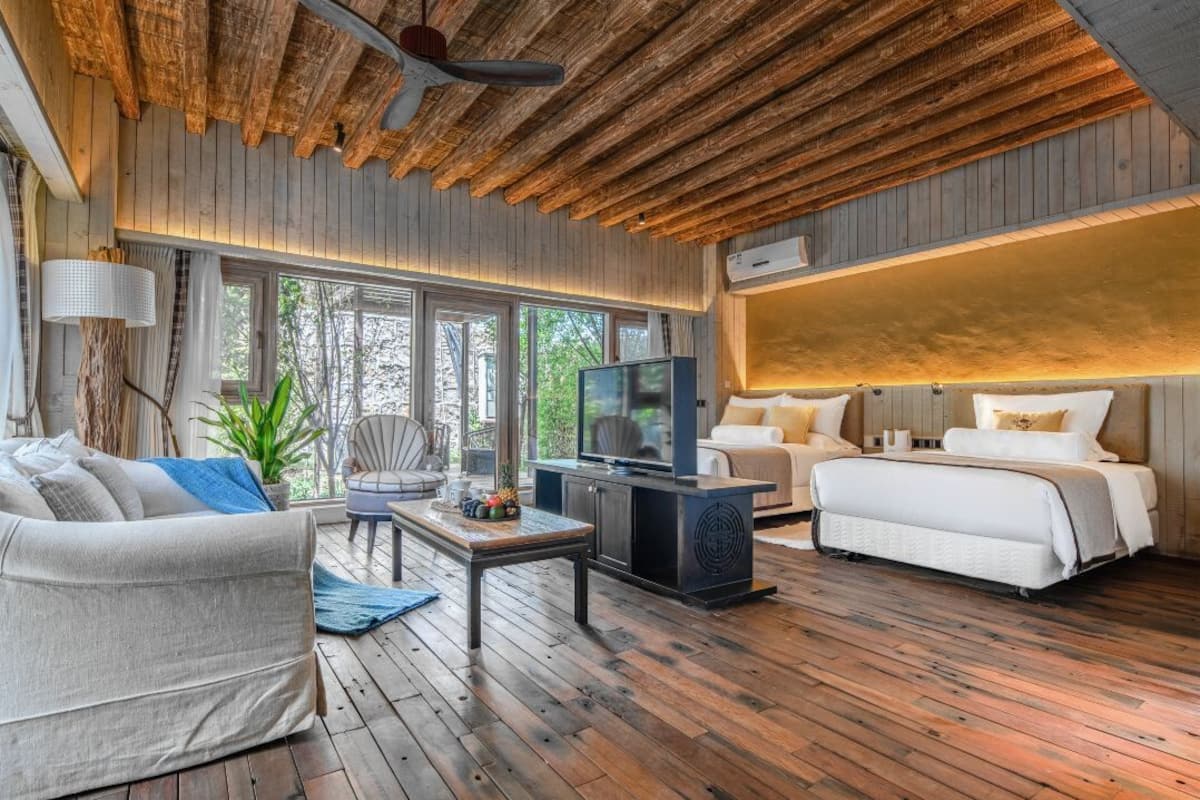 Une chambre moderne avec un plafond en bois, un canapé, un lit, une télévision et une grande fenêtre.