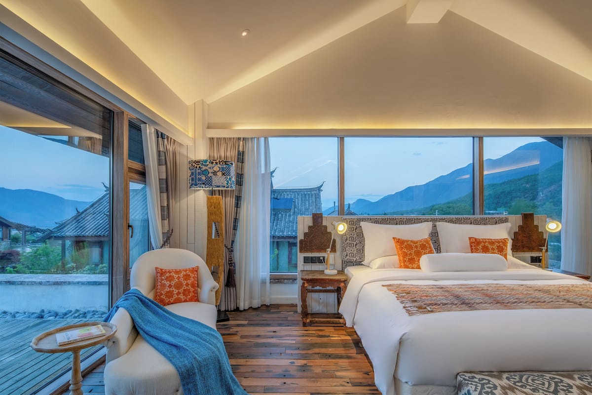 Une chambre d’hôtel moderne dotée d’un grand lit, d’un canapé et offrant une vue sur une architecture traditionnelle.
