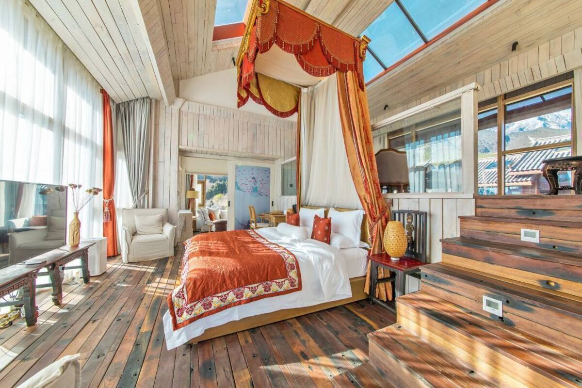 Une chambre spacieuse avec un grand lit, un plancher en bois et un lit à baldaquin.