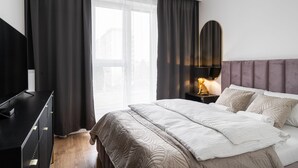 Une chambre d’hôtel moderne avec un grand lit, une télévision et une table de chevet avec une lampe.