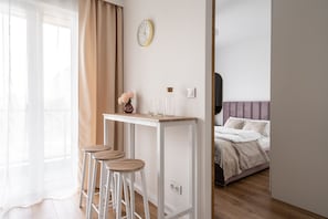 Relax in a serene space with a comfortable bed, a stylish desk, and a beautiful vase with flowers.