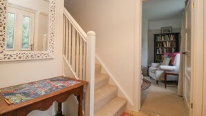 A staircase with a wooden railing, a table with a puzzle, and a bookshelf in the adjacent room.