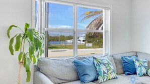 A room with a grey sofa, a large window, and a potted plant.