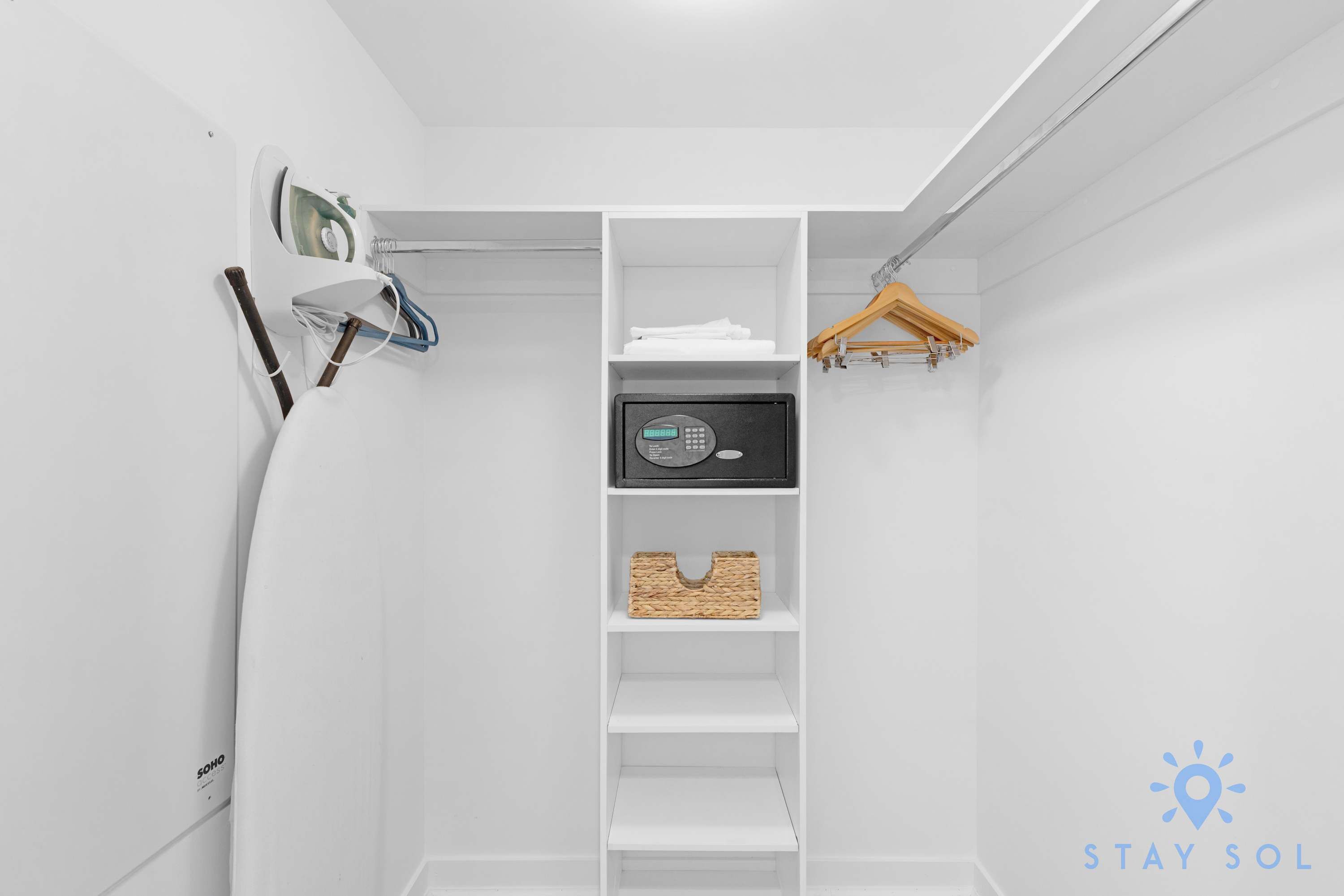 A white closet with shelves, a hanging rack, and a microwave.
