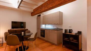 Een moderne keuken met houten balken, een eetgedeelte met een ronde tafel en stoelen, en inbouwapparatuur.