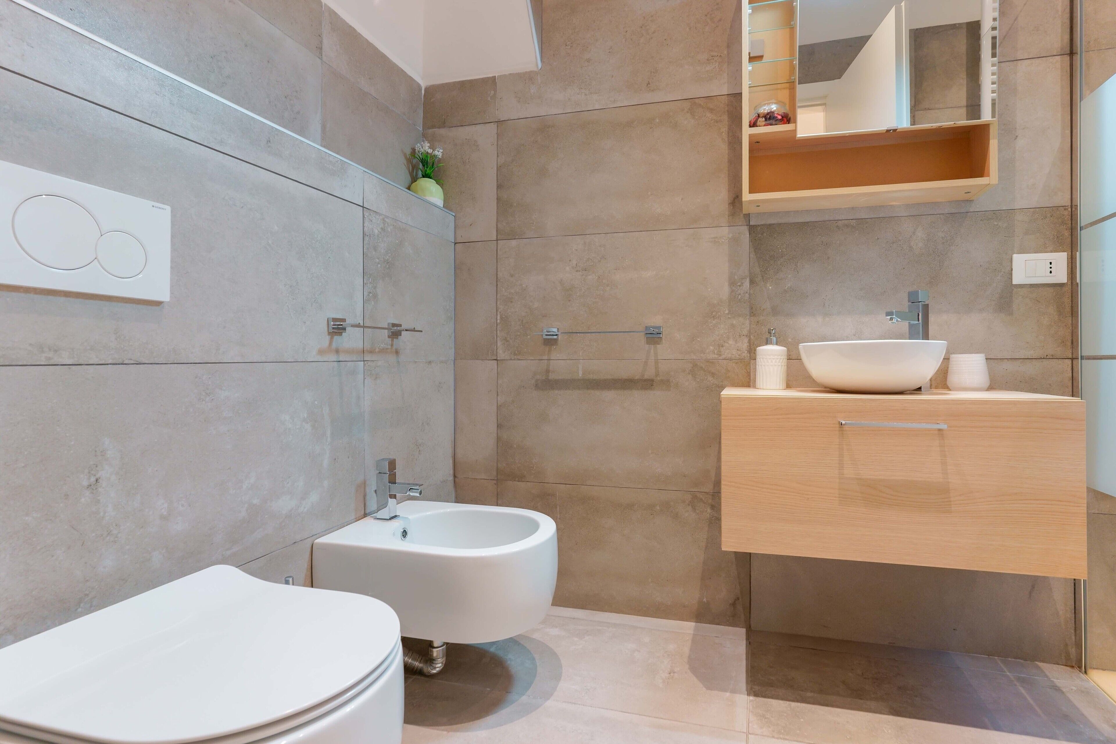 Une salle de bain moderne équipée d’un bidet, de toilettes, d’un lavabo et d’un miroir.