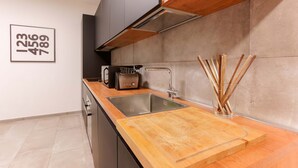 Una cocina moderna con encimera de madera, pileta de acero inoxidable y un tostador.