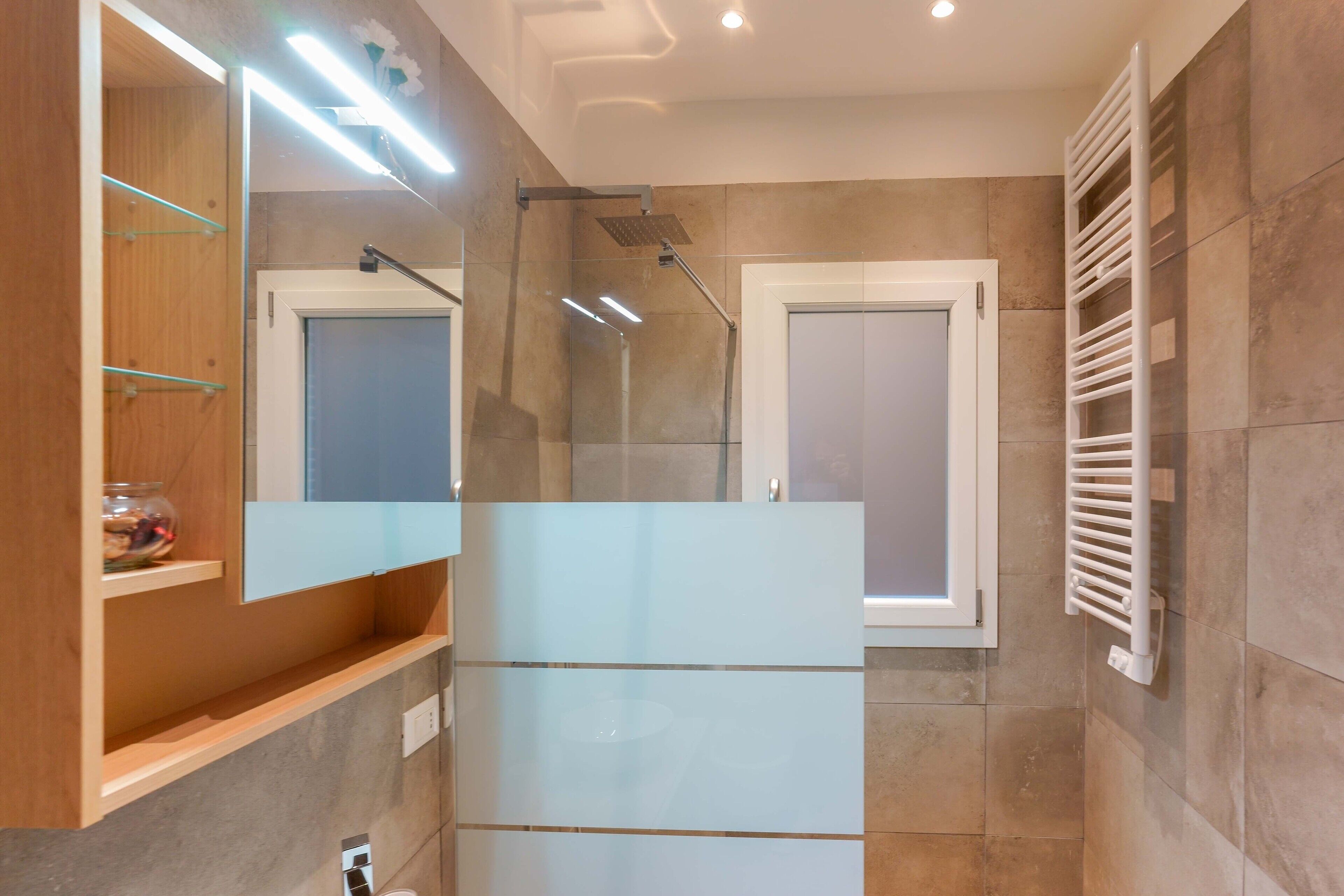 Une salle de bain moderne avec une douche à parois de verre, un meuble-lavabo intégré avec un miroir et un porte-serviettes.