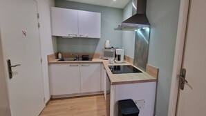 A compact kitchen with white cabinets, a microwave, a coffee maker, and a stainless steel range hood. - Le T2 A du Meysse (Meysse)