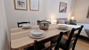 A dining area with a wooden table set for two, a stainless steel pot, and white plates and glasses. - Le T2 A du Meysse (Meysse)