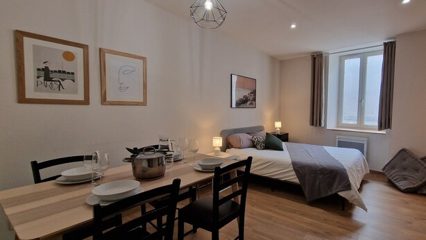 A modern bedroom with a bed, bedside table, and a window. - Le T2 A du Meysse (Meysse)
